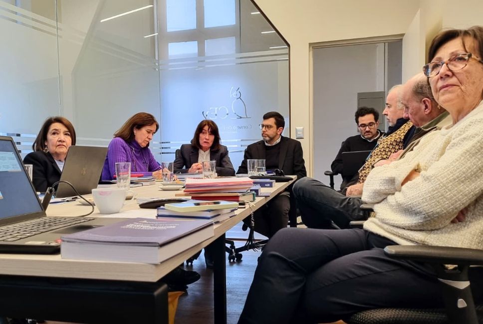 En la imagen podemos apreciar que sentadas y sentados entorno a la mesa de reuniones en la oficina del Consejo de Evaluación, se encuentran las académicas Jenny Fiedler, Maricruz Gómez de la Torre y Carmen Sotomayor. También está la prorrectora Alejandra Mizala y el director ejecutivo de Acreditación Institucional, Thomas Griggs. 